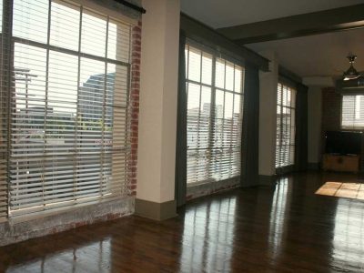A photo of a living room in Big Lick Junction with hardwood floors, exposed brick, and three floor-to-ceiling windows